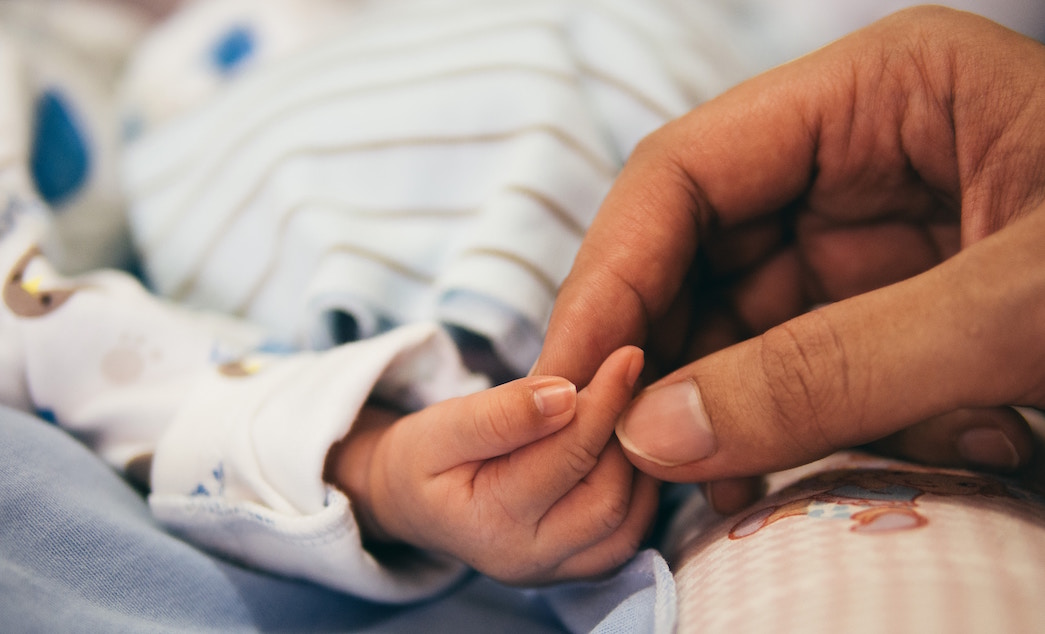 Understanding Birth Injuries. A mother holds hands with her newborn baby.