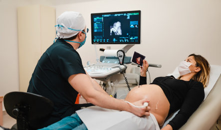 Doctor giving pregnant woman ultrasound.