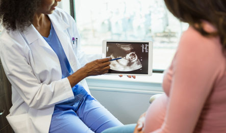 A pregnant mother receives improper prenatal care from her female doctor as they review an ultrasound in the doctor's office.
