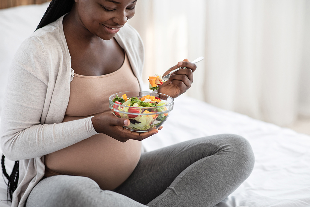 pregnant woman eating salad to follow Gestational Diabetes Guidelines