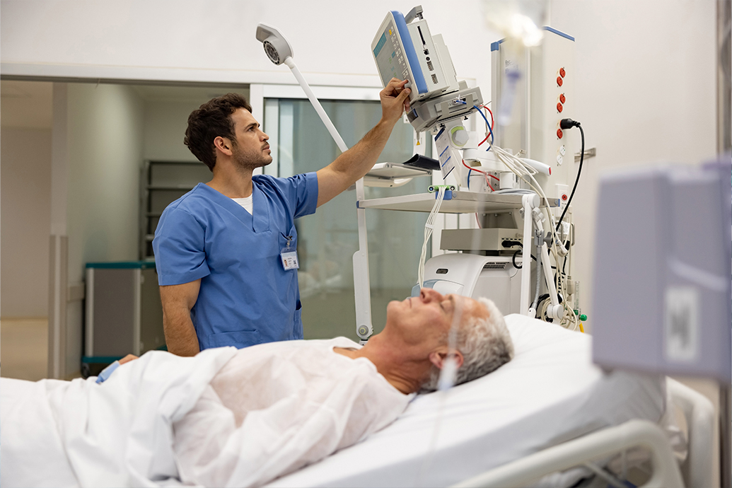 male nurse checking vitals while older gentleman is laying in a bed to avoid nursing malpractice