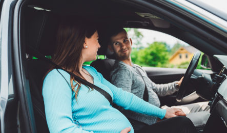 man and pregnant woman putting on seatbelts